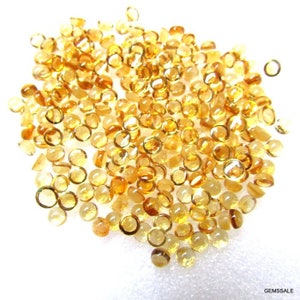 May include: A large pile of round, translucent, yellow gemstones. The gemstones are smooth and have a slight sparkle.