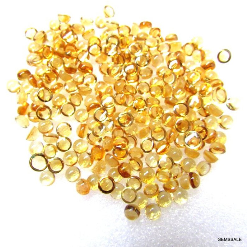May include: A large pile of round, translucent, yellow gemstones. The gemstones are smooth and have a slight sparkle.