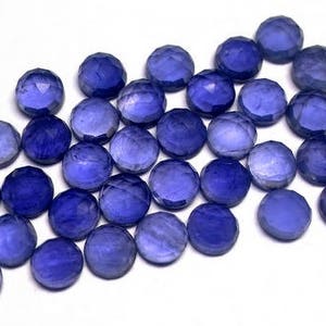 May include: A collection of 25 faceted round blue gemstones. The gemstones are approximately 6mm in diameter and have a variety of shades of blue.