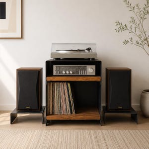 Könnte beinhalten: Ein schwarzer Audio-Ständer aus Metall mit zwei Holzregalen, auf dem sich oben ein silberner Plattenspieler, in der Mitte ein silberner Receiver und unten eine Sammlung von Schallplatten befindet, flankiert von zwei schwarzen Lautsprechern.