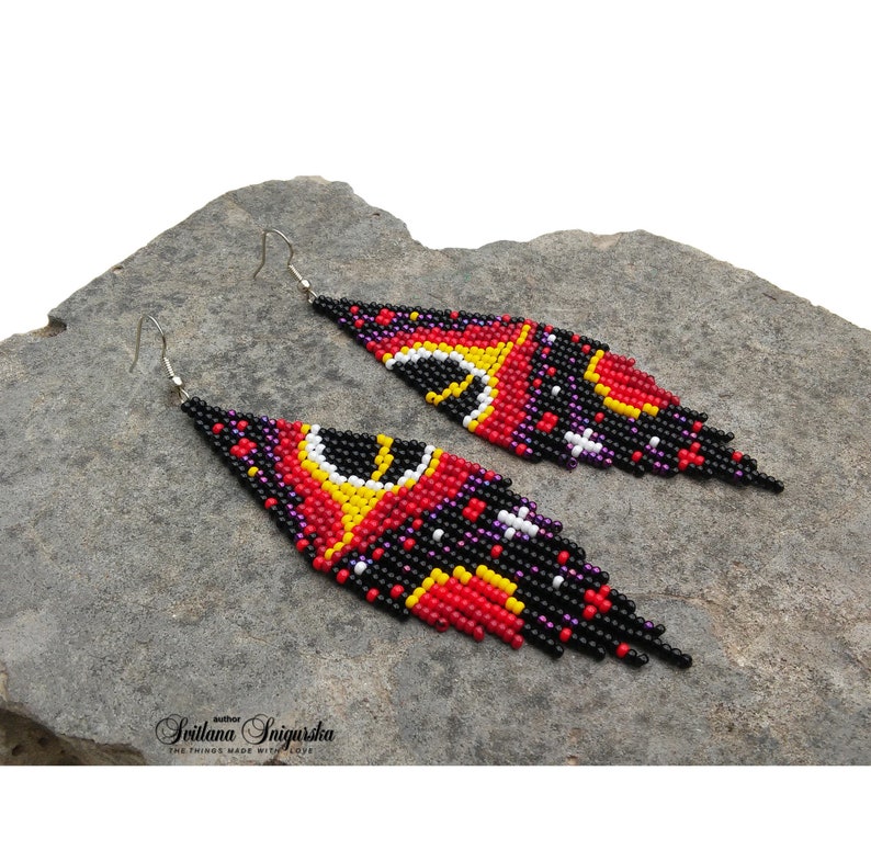 Handwoven black hole beaded earrings with red, gold and black cosmic galaxy design, long fringe seed bead statement jewelry on silver-plated hooks.