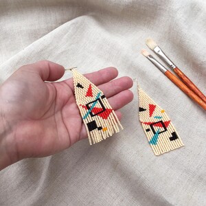 Abstract geometric seed bead earrings inspired by Bauhaus design, featuring ivory, black, red and turquoise color blocks with 18K gold-plated ear hooks.