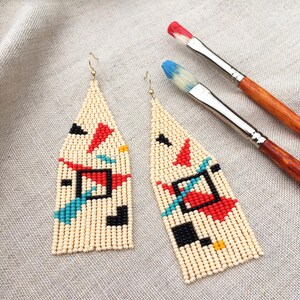 Abstract geometric seed bead earrings inspired by Bauhaus design, featuring ivory, black, red and turquoise color blocks with 18K gold-plated ear hooks.