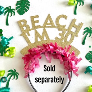 May include: Gold glitter headband with the text "Beach I'm 30" and pink tissue paper streamers. Sold separately.