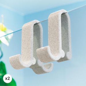 以下が含まれることがあります： 斑点模様の白いシャワーフック2個。フックはシャワーのドアやその他のガラス面に掛けるように設計されています。