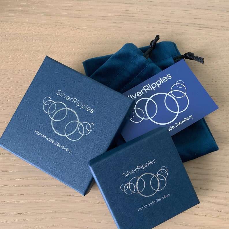 Może przedstawiać: Dwa niebieskie pudełka z logo "SilverRipples Handmade Jewellery" i niebieska aksamitna torebka z logo "SilverRipples Handmade Jewellery".