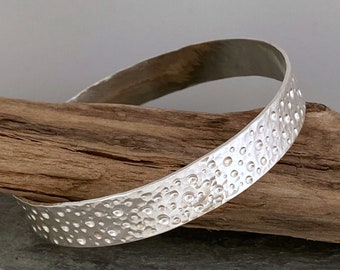 Wide hammered silver bangle with a unique bubbles pattern, made from recycled sterling silver