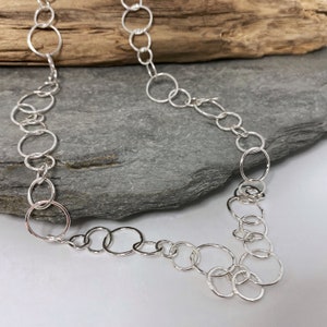 Handmade hammered silver delicate chain necklace made from three sizes of round links and fastening with an easy to use yet secure hook