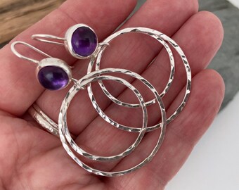 Large silver hoop earrings topped with vibrant purple Amethyst gemstones. Amethyst earrings. Large round earrings. Unique Amethyst earrings.