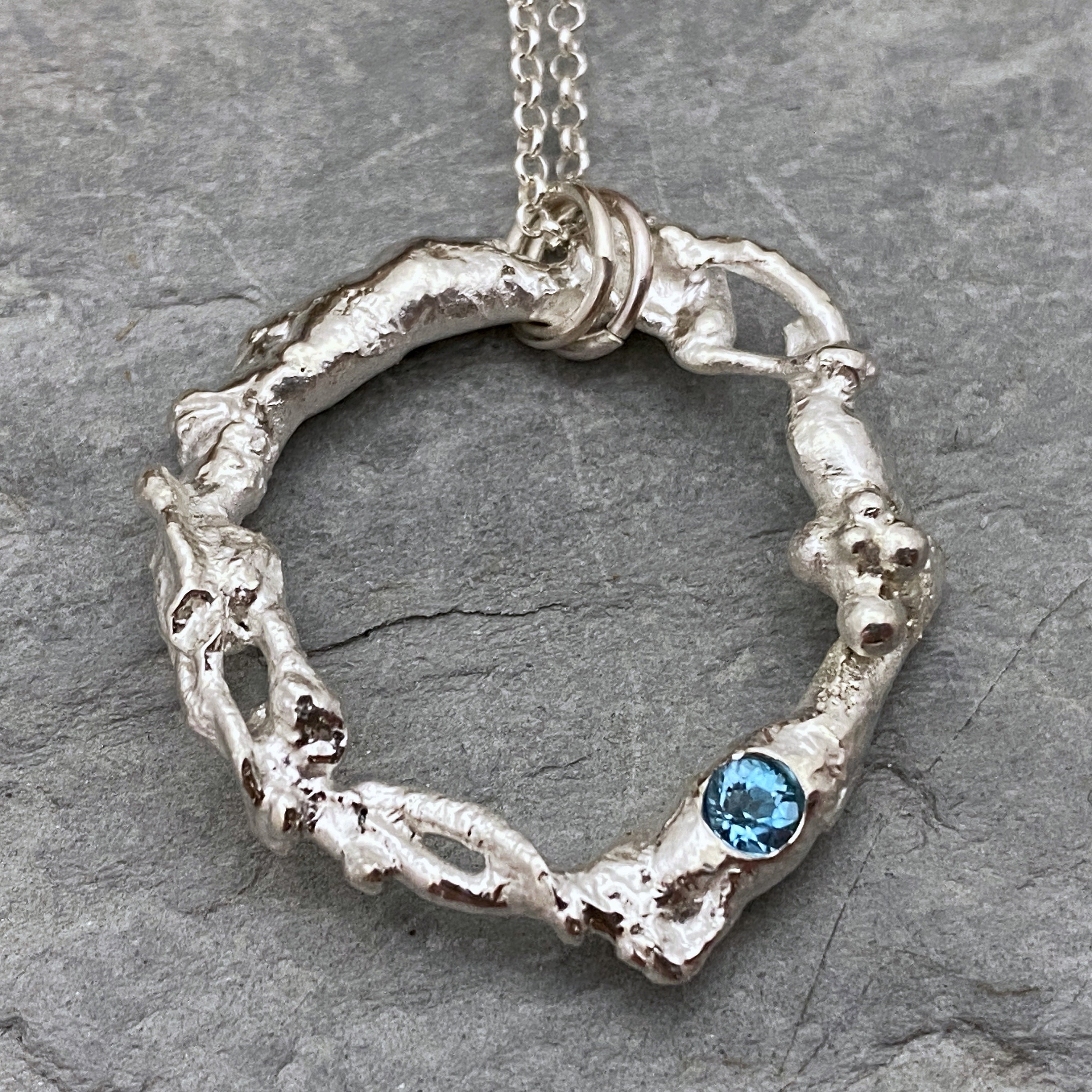 Molten Silver Circle Necklace Set With A Bright Blue Topaz Gemstone, Organic Pendant