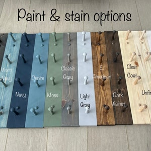 Pu&ograve; includere: Un appendiabiti in legno con 12 ganci, che mostra 12 diverse opzioni di vernice e tinta. Le opzioni includono nero, ebano, blu navy caldo, blu navy, denim, muschio, grigio classico, grigio chiaro, El American, noce scuro, vernice trasparente, non finito, bianco tinto e bianco.