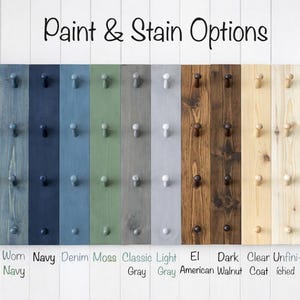 May include: A display of wooden planks with various paint and stain options. Colors include black, ebony, navy, denim, moss, gray, and walnut. Each plank has pegs for hanging items. Text at the top reads "Paint & Stain Options."