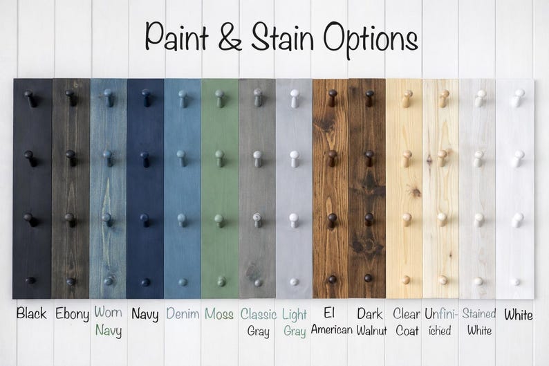 May include: A display of wooden planks with various paint and stain options. Colors include black, ebony, navy, denim, moss, gray, and walnut. Each plank has pegs for hanging items. Text at the top reads "Paint & Stain Options."
