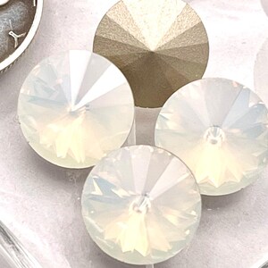 May include: Three round, faceted, iridescent white crystals with a pointed back, arranged alongside a silver 1936 Mercury dime for scale. The crystals exhibit a clear, reflective surface with subtle rainbow light refractions and a conical shape.