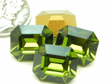 May include: Three emerald green faceted gemstones in a square shape, with a gold-colored metal setting in the background. The gemstones are approximately the size of a U.S. dime.