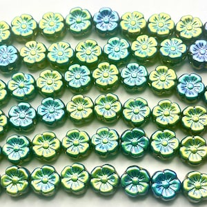 May include: Rows of iridescent flower-shaped beads in shades of green, blue, and yellow. The beads have a glossy finish and are strung together, perfect for jewelry making or crafting projects.