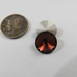 May include: A 1936 Mercury dime next to two faceted crystal stones. One is silver, the other is a dark red-brown color. The crystals have a starburst pattern. The coin is bronze-colored.