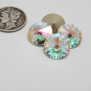 Puede incluir: Una moneda de plata junto a tres cristales redondos iridiscentes. Los cristales tienen un diseño facetado, que refleja colores rosa, verde y amarillo. La moneda es una moneda de diez centavos Mercury, fechada en 1936.