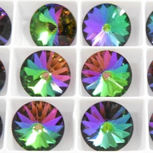 Pode incluir: Uma coleção de doze strass de cristal redondos e iridescentes. Cada strass é multicolorido, com tons de roxo, verde, laranja e azul irradiando do centro. Os cristais são colocados em compartimentos quadrados brancos individuais.
