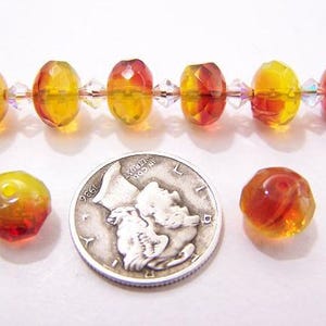 Puede incluir: Un hilo de cuentas de vidrio facetadas amarillas y rojas con espaciadores de cristal transparente. También hay dos cuentas sueltas y una moneda de plata. Las cuentas tienen un aspecto cálido, como ámbar.