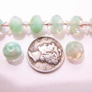 Puede incluir: Un hilo de cuentas facetadas de color verde claro con espaciadores de cristal transparente. También hay dos cuentas sueltas y una moneda de plata. Las cuentas son translúcidas y la moneda está fechada en 1936.