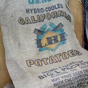 Puede incluir: Un saco de arpillera con el texto "U.S. NO. 1 HYDRO-COOLED CALIFORNIA LBI POTATOES GROWN & PACKED BY BIG L PACKER EDISON, CA 93220 MAY HAVE BEEN TREATED WITH CHLORPROPHAM TO PREVENT SPROUTING NET WT. 100 LBS - 1/4"