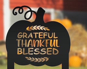 May include: Black metal pumpkin silhouette with a gold inscription that reads "Grateful Thankful Blessed".