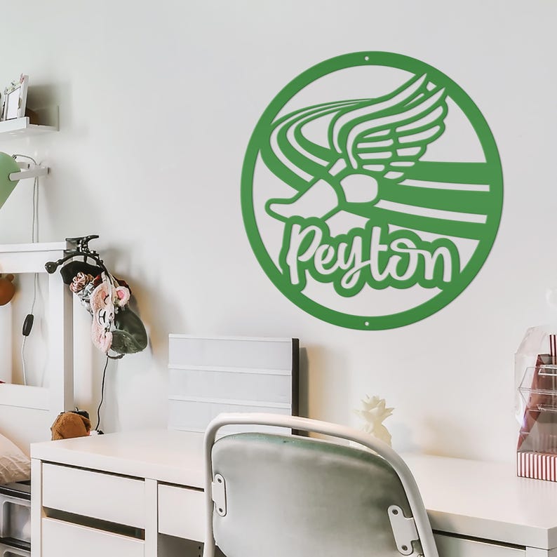 Puede incluir: Decoraci&oacute;n de pared verde y circular con una zapatilla de correr alada estilizada y el nombre "Peyton" en letra cursiva. El dise&ntilde;o est&aacute; cortado de una sola pieza de material y montado en una pared blanca, creando un efecto de sombra. El tema general es el deporte o el atletismo.