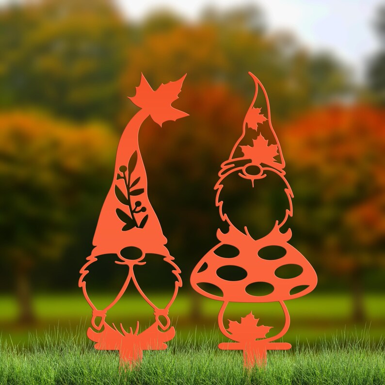 May include: Two orange metal garden gnomes. One gnome has a tall hat with a leaf and a floral design. The other gnome has a mushroom-shaped body and a hat with leaf cutouts. Both gnomes have beards and are designed to be placed in a garden.