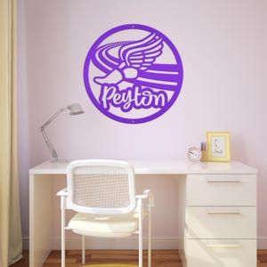 Puede incluir: Un letrero de pared circular de color morado con un dise&ntilde;o recortado de una zapatilla de correr alada y el nombre Peyton en letra cursiva. El letrero tiene dos peque&ntilde;os orificios en la parte superior e inferior para su montaje.