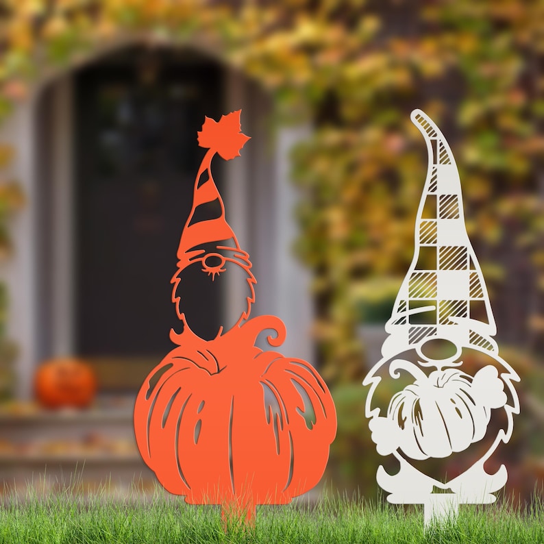 May include: Two metal lawn ornaments in the shape of gnomes. One is orange with a pumpkin body and striped hat. The other is white with a plaid hat and pumpkin body. Both are designed for outdoor fall decor.