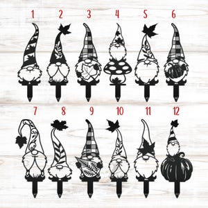 May include: A collection of twelve black metal garden gnomes with various hat designs, including plaid, leaf, and pumpkin motifs. Each gnome has a stake for easy placement in a garden or yard. The gnomes are numbered for selection.