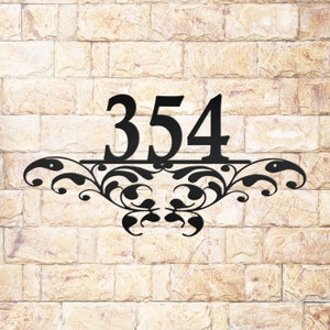 May include: Black metal house number plaque with the number 354 and a decorative floral design.