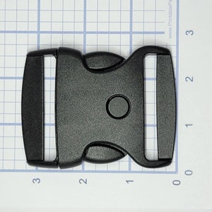 May include: Black plastic side release buckle. The buckle is approximately 5 cm long and 2.5 cm wide.