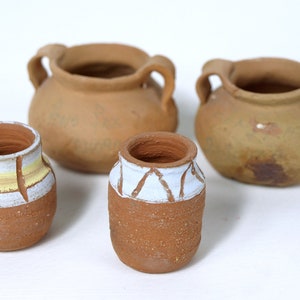 May include: Four terracotta pots, two with handles, one with white and yellow stripes, and one with white geometric designs.