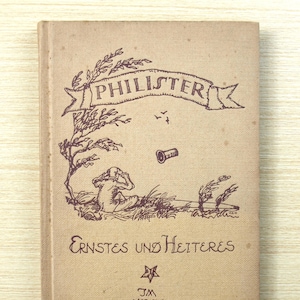May include: A vintage book with a tan cover featuring a brown illustration and text. The title "PHILISTER" is displayed on a banner above a drawing of a person, tree, and other elements. The book's title is "Ernstes und Heiteres".