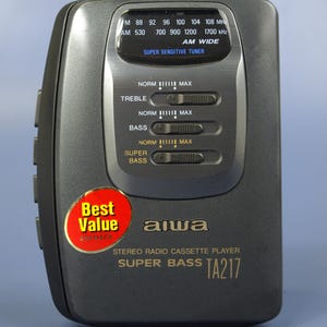 Może przedstawiać: Ciemnoszary odtwarzacz kaset stereo Aiwa, model TA217, z czerwoną i żółtą naklejką "Best Value". Posiada radio FM/AM, regulację tonów wysokich, niskich i super basów.