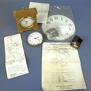May include: A collection of clock components and assembly instructions. Includes a wooden clock, a clock face, and a small round clock with a gold-colored bezel. The assembly instructions are from Craft Products Company.