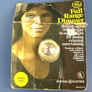 Puede incluir: Atenuador de rango completo General Electric vintage empaquetado en un respaldo de cartón. El embalaje presenta un retrato de mujer y el texto "Ajusta la luz de brillante a apagada para cenar, relajarse, entretenerse". El atenuador es un interruptor de tres vías.