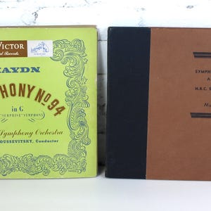 May include: Two vintage vinyl record covers featuring classical music. The left cover is green with gold lettering and features the text "HAYDN SYMPHONY NO. 94" and "Boston Symphony Orchestra". The right cover is brown with black lettering and features the text "HAYDN SYMPHONY No. 104 in C MAJOR" and "NBC Symphony Orchestra".