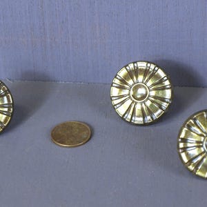 May include: Three gold-toned metal drawer pulls with a decorative sunburst design.