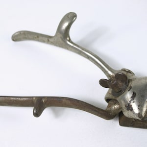 May include: Antique silver-toned hair clipper with a long handle and a serrated blade. The clipper has a small knob on the side for adjusting the blade.