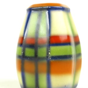 Może przedstawiać: Kolorowa solniczka w stylu vintage z wzorem w kratę. Solniczka ma kremową podstawę z pasmami czerwieni, zieleni i pomarańczy, obrysowanymi ciemnoniebieskimi liniami. Górna część jest w jednolitym pomarańczowym kolorze.