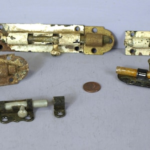 May include: Five antique door latches in various styles and finishes. Two are white with brass accents, one is black with a wooden handle, and two are rusty brown metal.