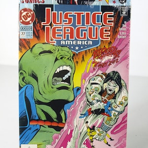 May include: A Justice League America comic book, issue #77, sealed in plastic. The cover features a green-skinned character screaming, and a battle scene with other characters. The top of the comic has the words "3 Comics" and images of Batman, Wonder Woman, and Superman.