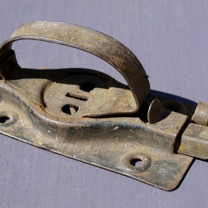 May include: A rusty metal latch with a handle and a locking mechanism. The latch is designed to be mounted on a door or gate.