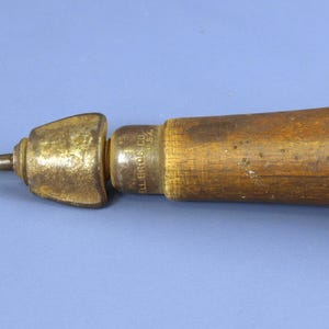 Könnte beinhalten: Ein Vintage-Handwerkzeug mit einer spitzen Metallahle, einem messingfarbenen Metallfutter und einem zylindrischen Holzgriff. Der Metallring in der Nähe des Griffs ist mit dem Text "MILLERS FALLS CO. MASS. U.S.A." geprägt.