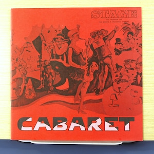 Puede incluir: Una portada de programa roja para la obra "Cabaret" con ilustraciones en blanco y negro de artistas. La palabra "STAGE" está en la parte superior, y "CABARET" en letras grandes en la parte inferior. El programa es para el Teatro Morris A. Mechanic.