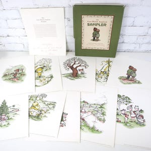 May include: A set of vintage prints with delightful illustrations. The prints show scenes with figures, trees, and landscapes. A green box with the text "Joan Walsh Anglund SAMPLER" is visible, alongside a sheet of text.