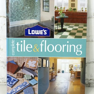 Könnte beinhalten: Ein Buch mit dem Titel "complete tile & flooring" mit Bildern von Badezimmern, Küchen und Fliesenmustern. Das Lowe's-Logo ist sichtbar. Das Buch zeigt eine Vielzahl von Fliesen- und Bodenbelagsdesigns.